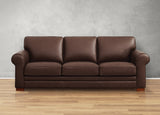 Brown leather sofa against a gray wall on a wooden floor