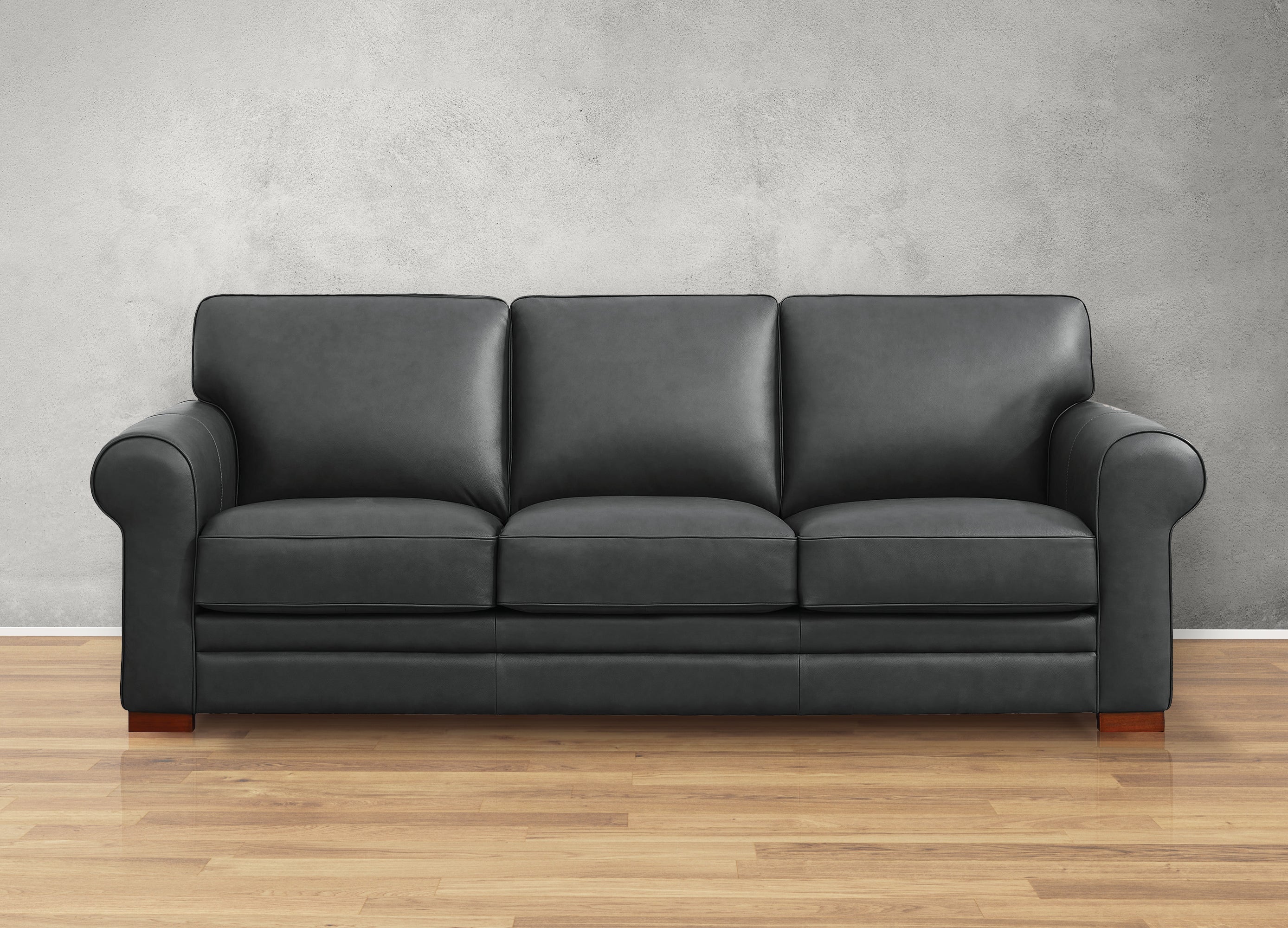 Gray leather sofa on a wooden floor with a gray wall background