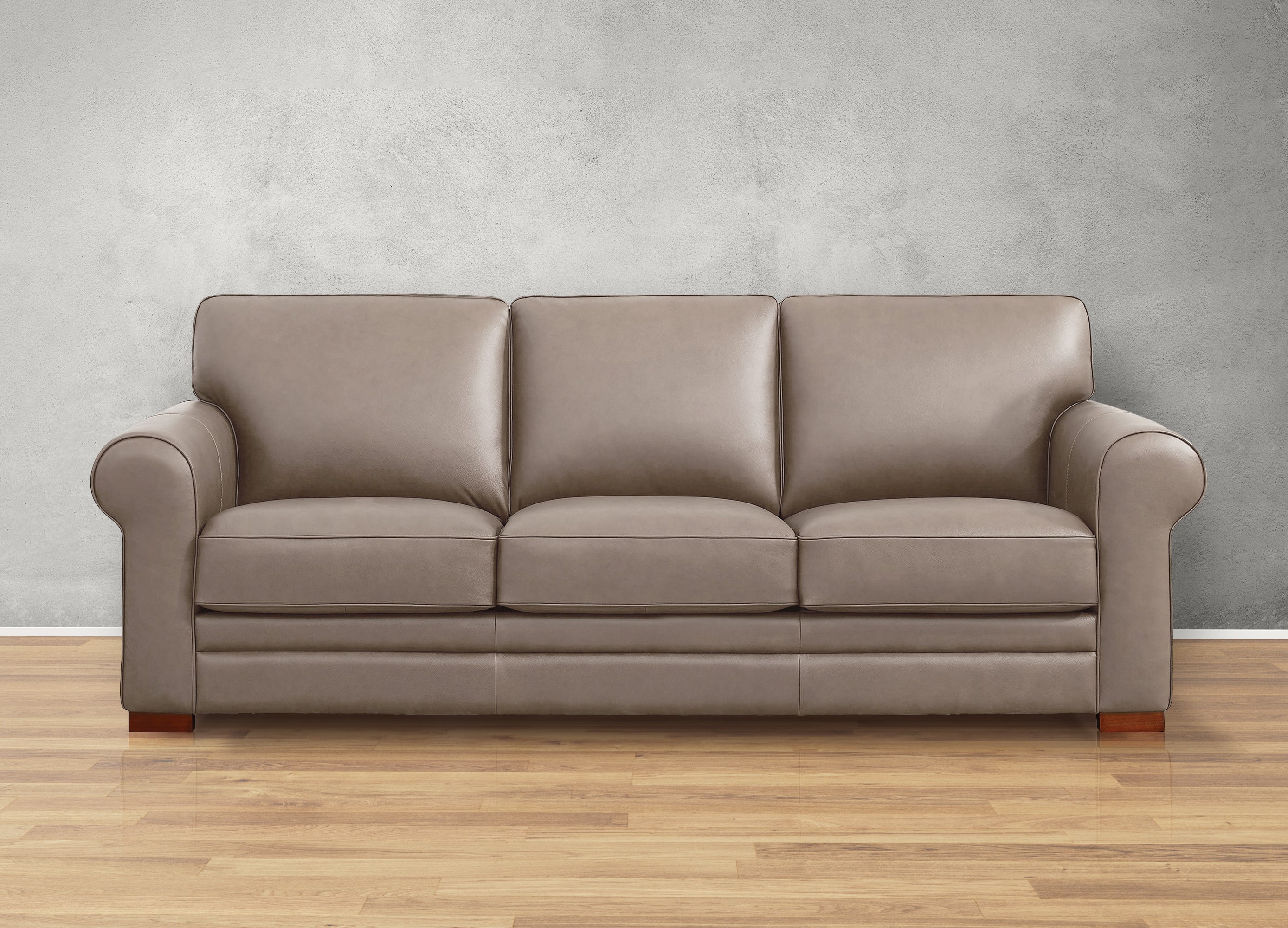 Gray leather sofa on a wooden floor with a gray wall background