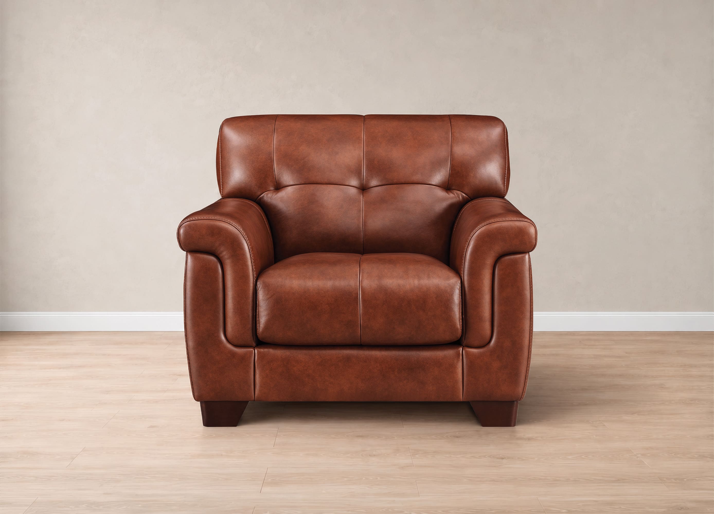 A brown leather armchair with tufted back cushions and rolled arms, shown from the front against a neutral beige wall and light wood floor.