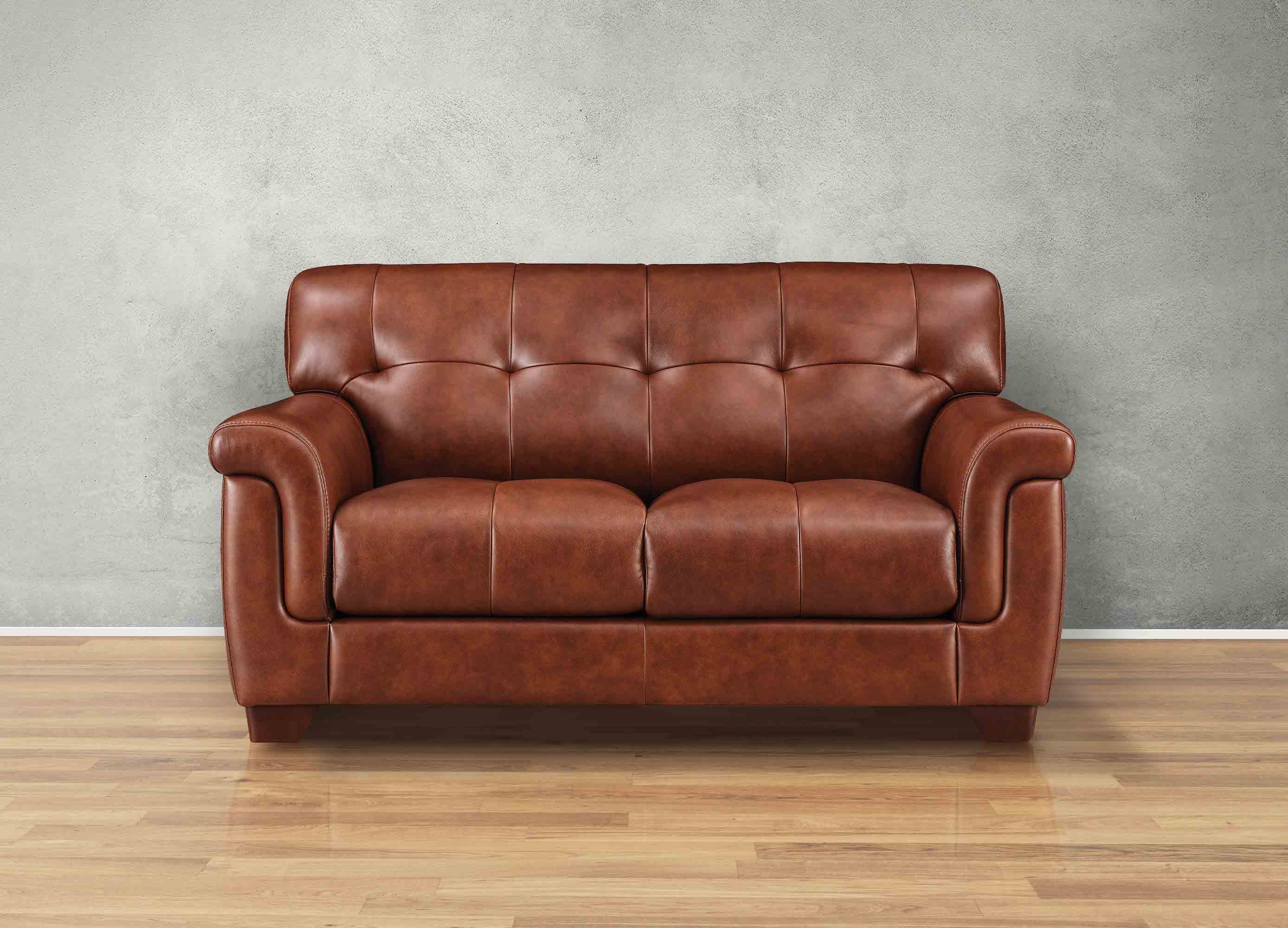 Brown leather sofa on a wooden floor with a gray wall background