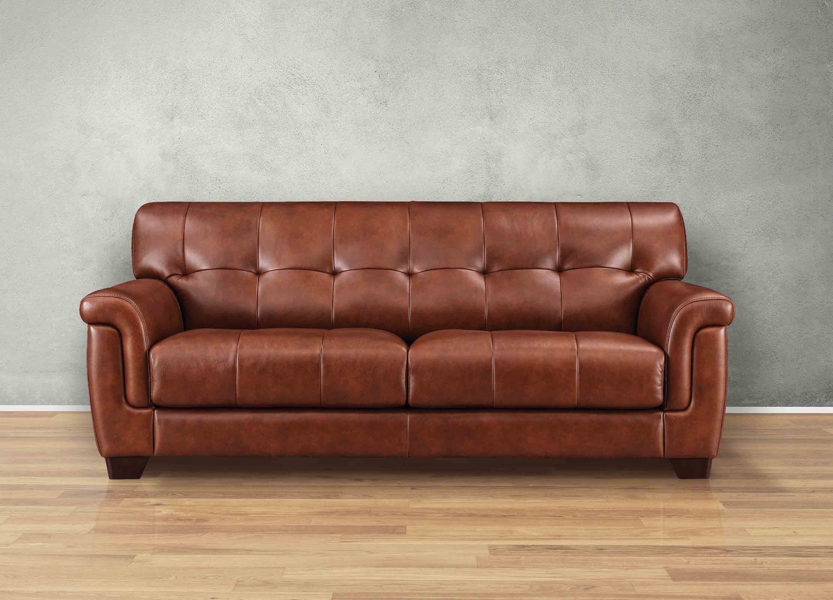 Brown leather sofa against a gray wall on a wooden floor