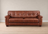 A brown leather sofa Marylynn with a tufted backrest and rolled arms, shown against a neutral beige wall and light wood floor.