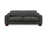 A modern three-seater sofa upholstered in dark charcoal gray fabric, featuring vertical channel tufting on the backrest and seat cushions, with dark brown wooden legs, shown against a plain white background.