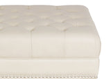 Close-up of a tufted white ottoman with decorative buttons on a white background