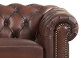 Close-up of a brown leather armchair with tufted backrest and nailhead trim.