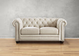 Beige tufted sofa on a wooden floor with a gray wall background