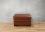 Brown leather ottoman on a wooden floor with a gray wall background
