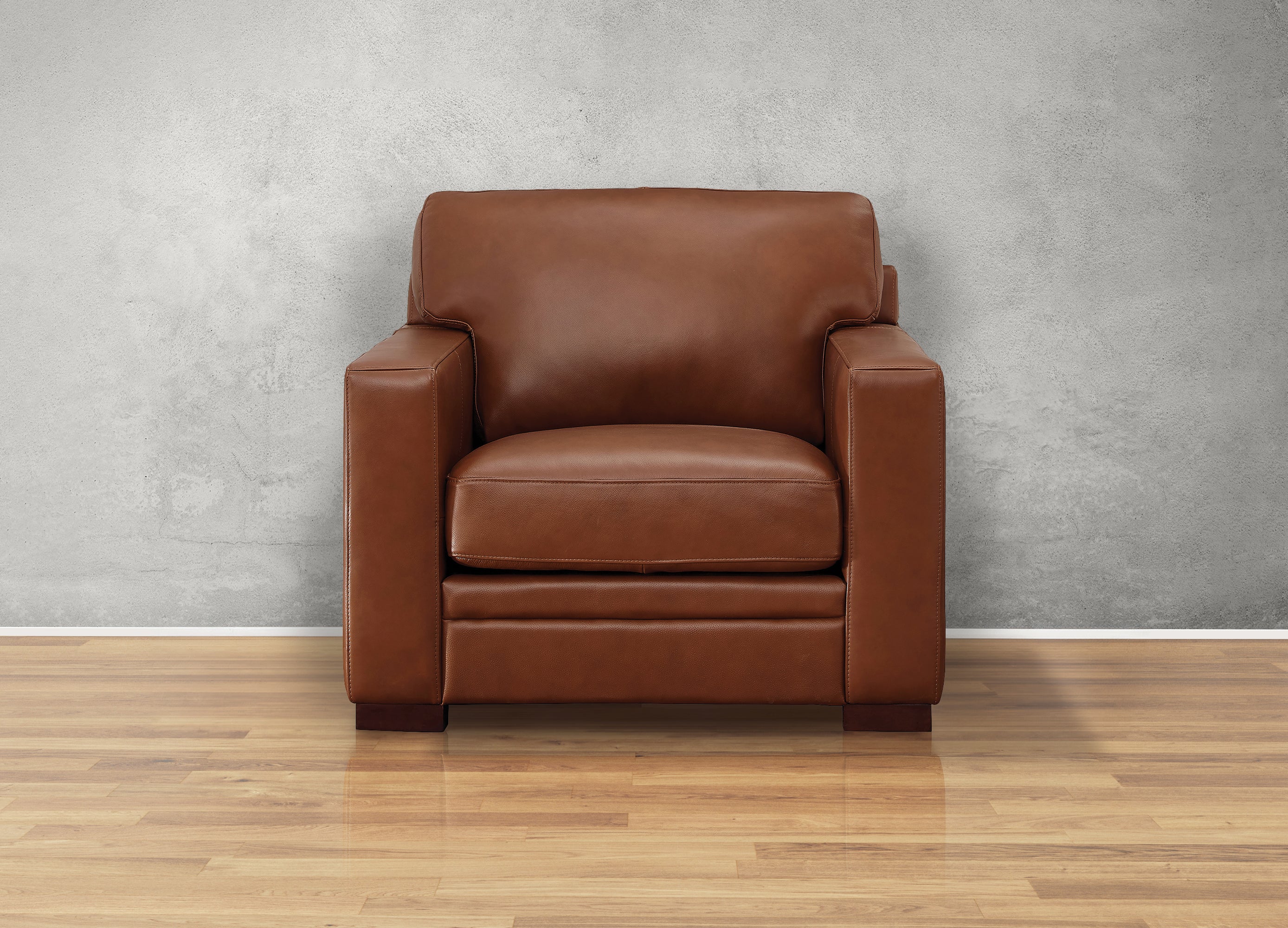 Brown leather armchair on a wooden floor with a gray wall background