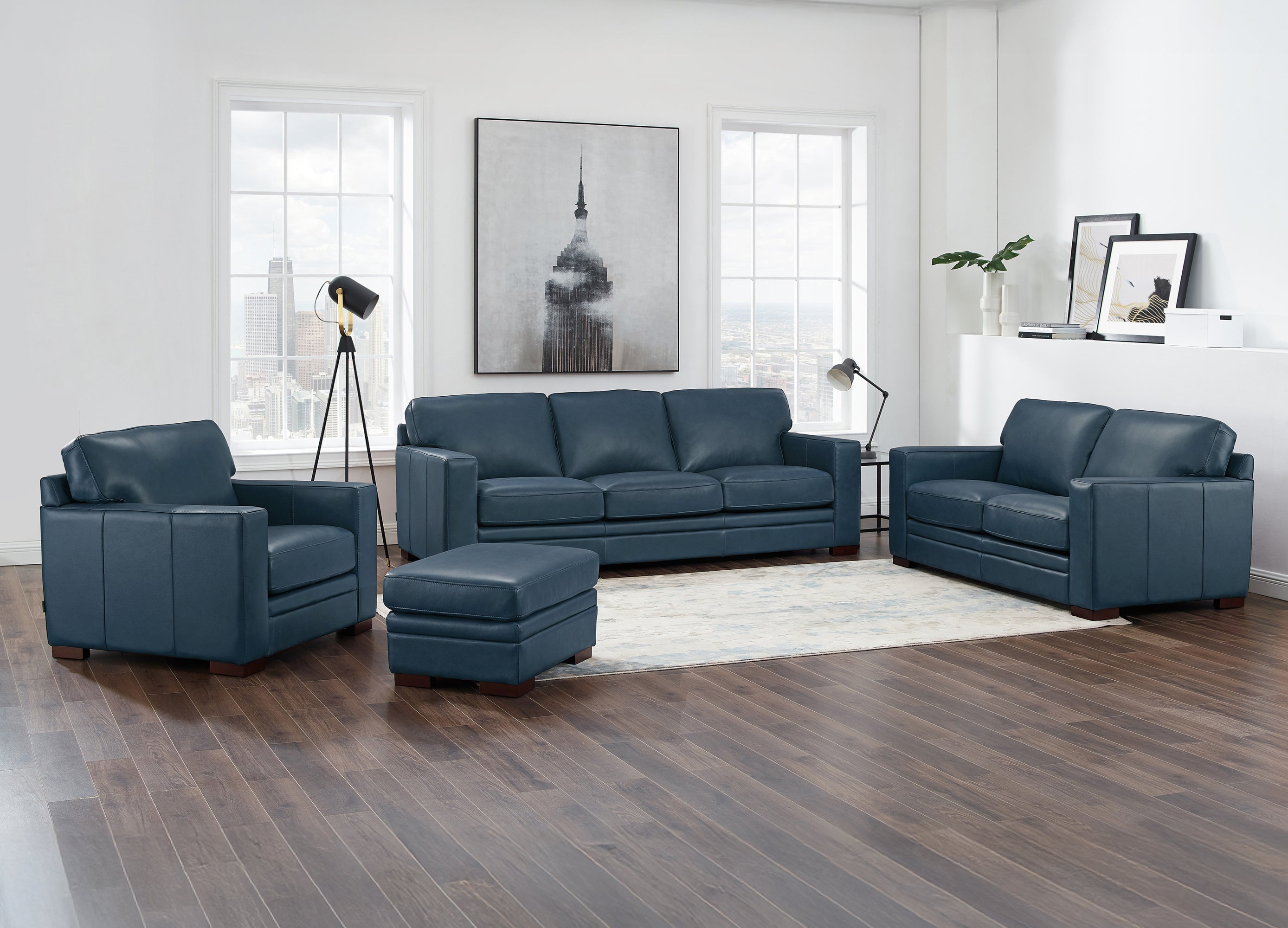 Blue leather sofa set in a modern living room with wooden flooring and large windows.