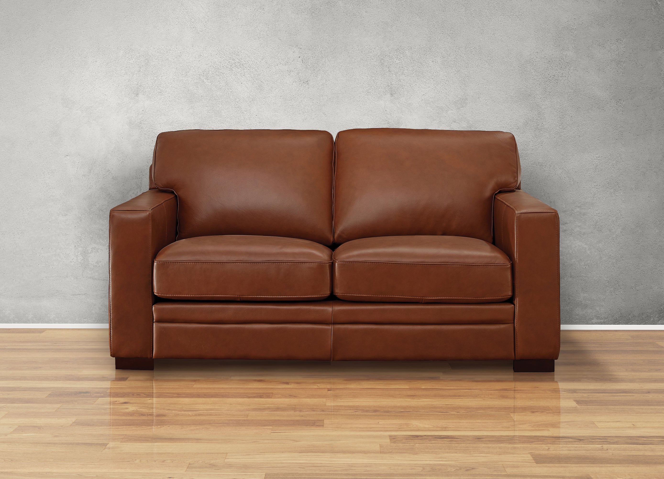Brown leather sofa on a wooden floor with a gray wall background