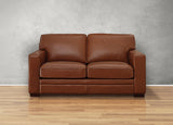 Brown leather sofa on a wooden floor with a gray wall background