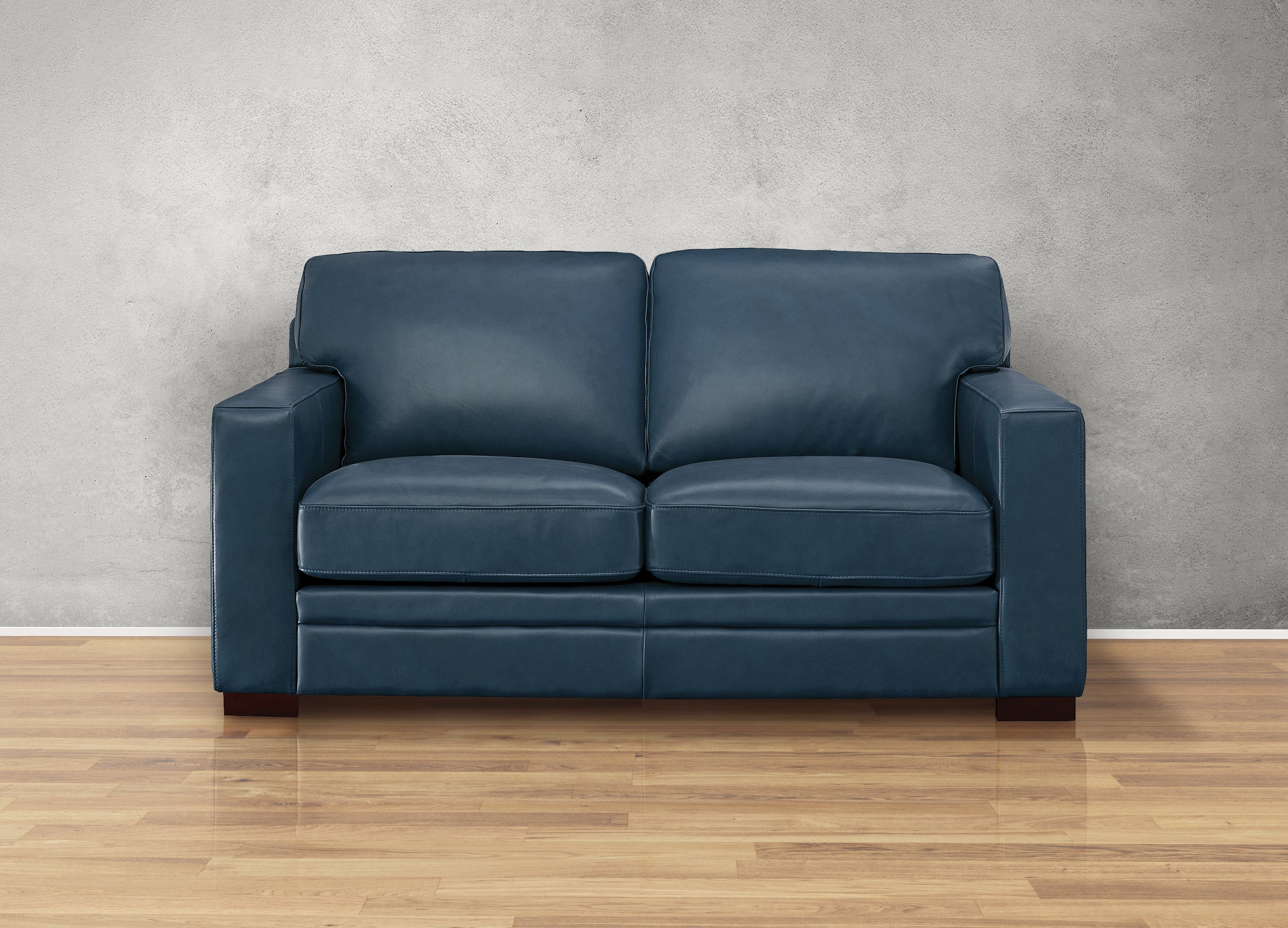 Blue leather sofa in a room with a gray wall and wooden floor