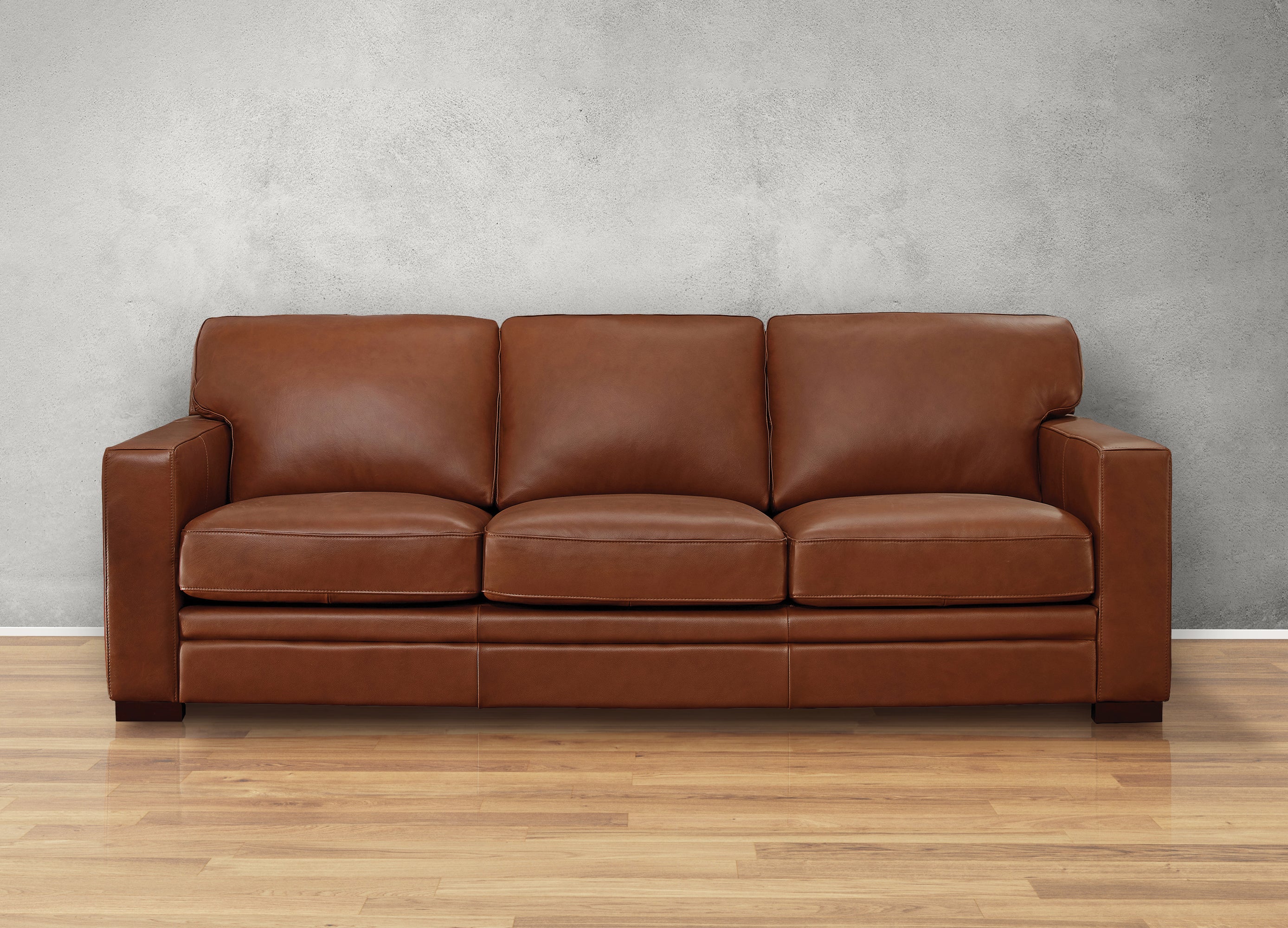 Brown leather sofa against a gray wall on a wooden floor