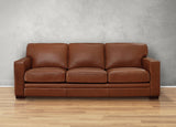 Brown leather sofa against a gray wall on a wooden floor