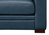 Close-up of a blue leather sofa corner with stitching detail.