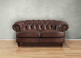 Brown leather sofa against a gray wall on a wooden floor