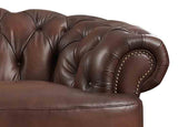 Close-up of a brown leather sofa with tufted backrest and nailhead trim.