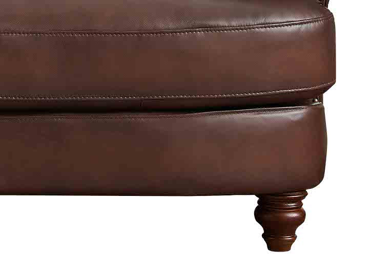 Close-up of a brown leather ottoman with visible stitching on a white background