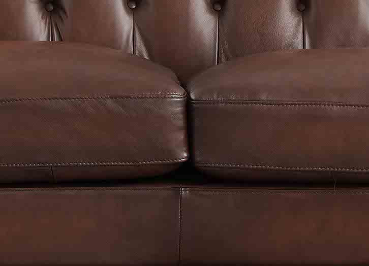 Close-up of a brown leather sofa with tufted backrest