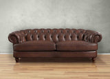 Brown leather sofa against a gray wall on a wooden floor